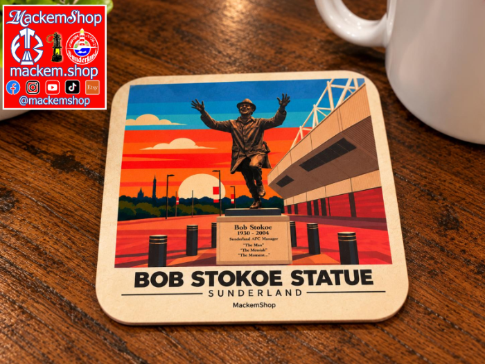 A square coaster featuring an illustrated Bob Stokoe Statue in Sunderland, placed on a wooden table next to a white mug. The coaster has rounded corners and the text 'BOB STOKOE STATUE SUNDERLAND' printed at the bottom.