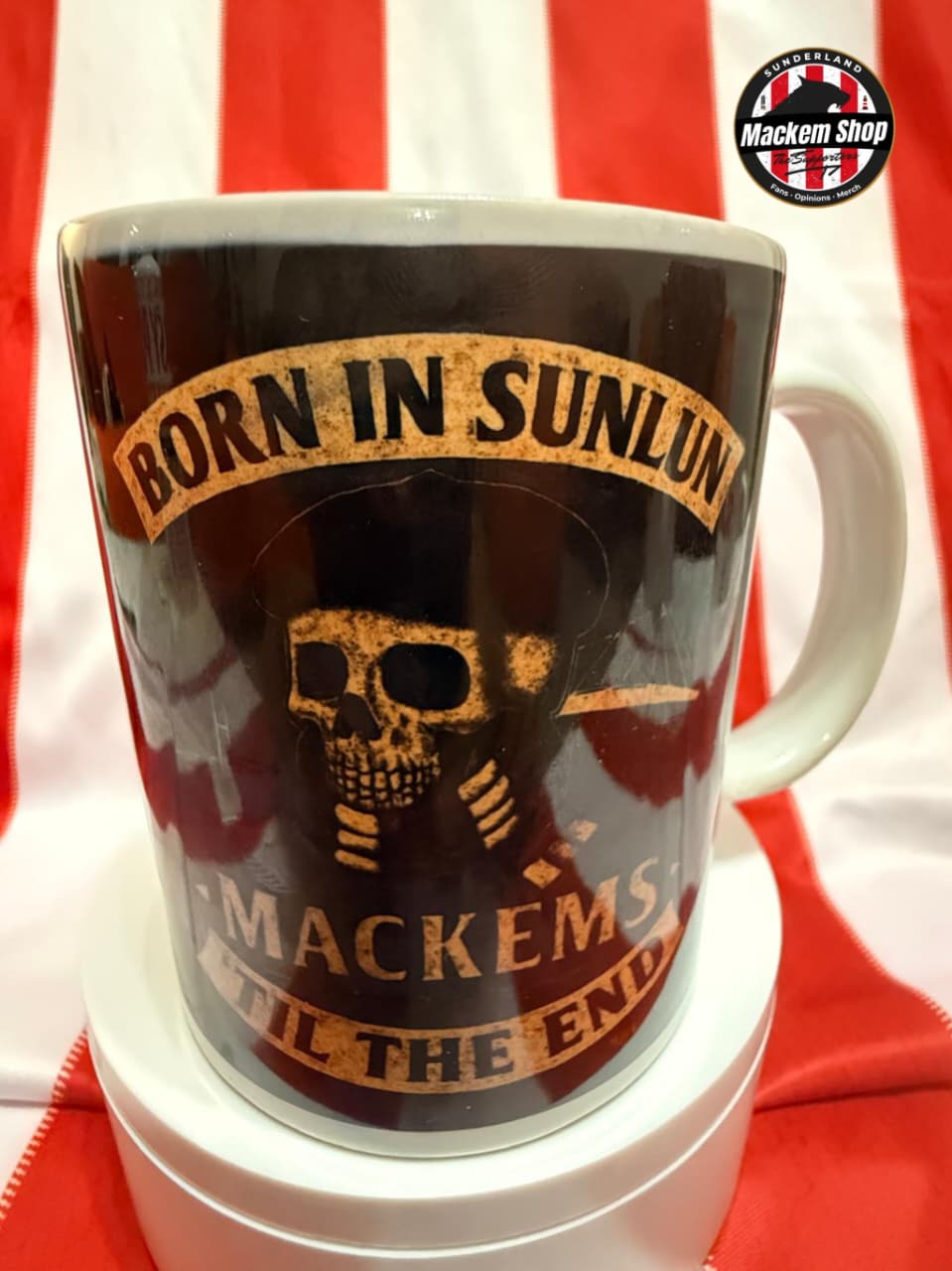 Mug with skull design and text 'Born in Sunllun, Mackems till the end' on a red and white striped background.