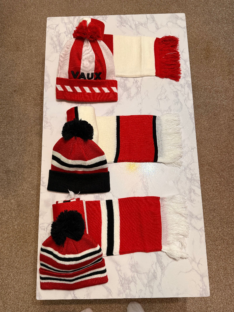 Set of red and white scarves and hats on a textured surface