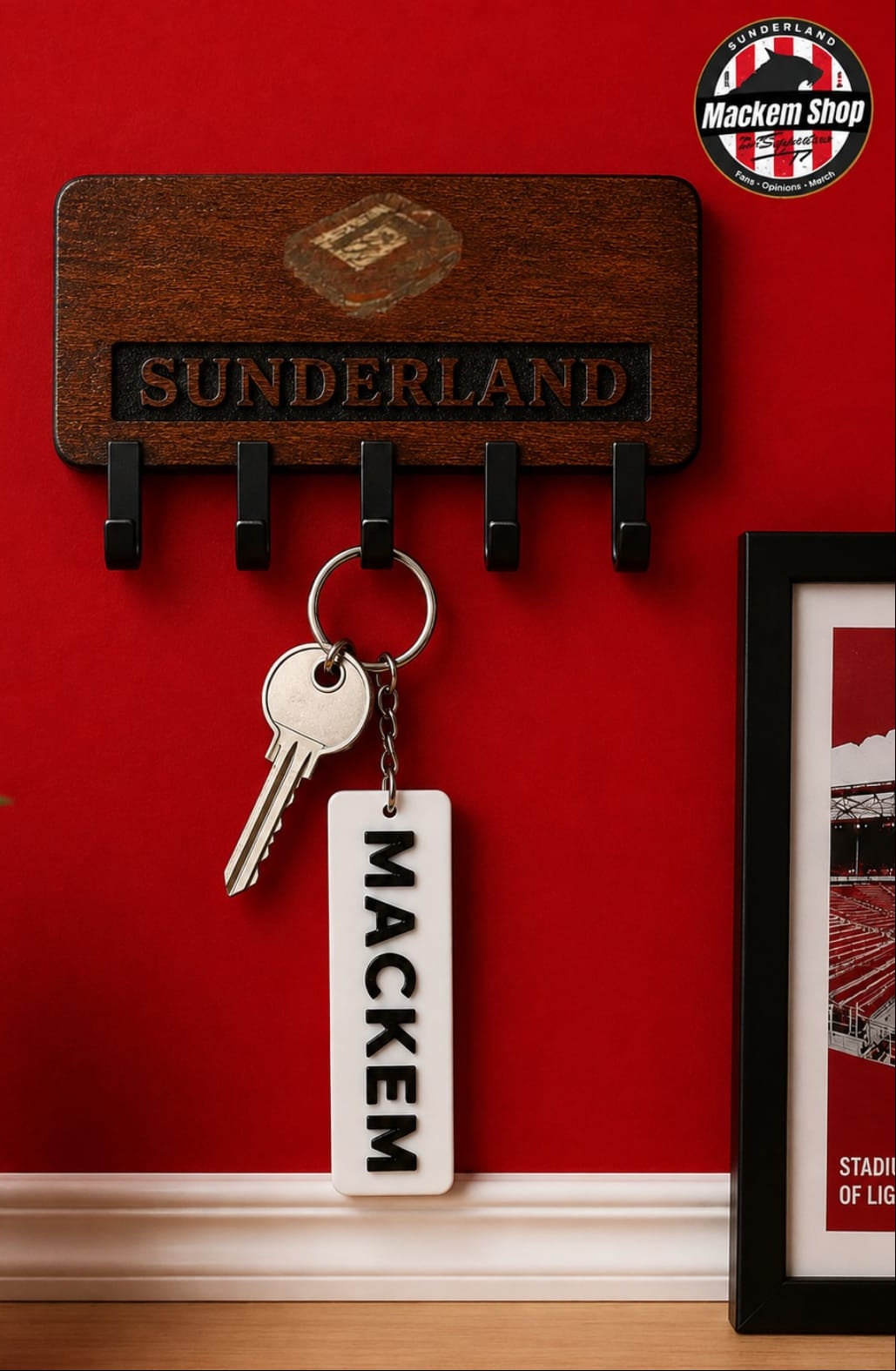 A wooden Sunderland key holder mounted on a red wall, holding a keyring with a white rectangular keychain that reads MACKEM. A Sunderland football club crest is visible on the pot and framed print, and a MackemShop logo appears in the top right corner.
