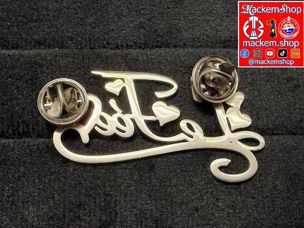 Enzo Le Fee Brooch put upside down on a dark grey surface with MackemShop Logo in the top right corner.