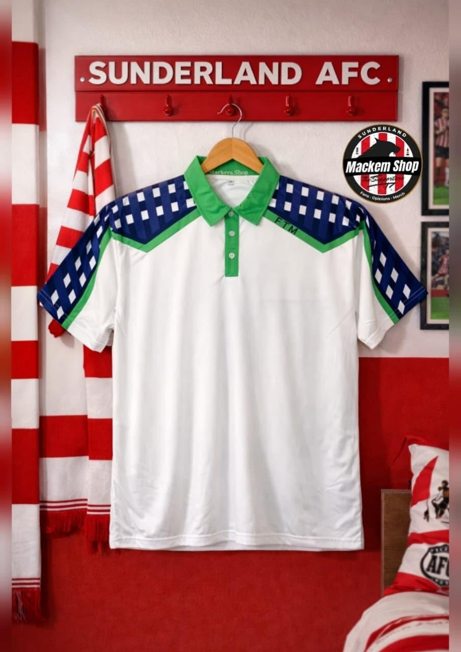 A white short-sleeve polo shirt with green and blue patterned shoulder panels hangs on a wooden hanger against a red wall. The shirt has a green collar and button placket.