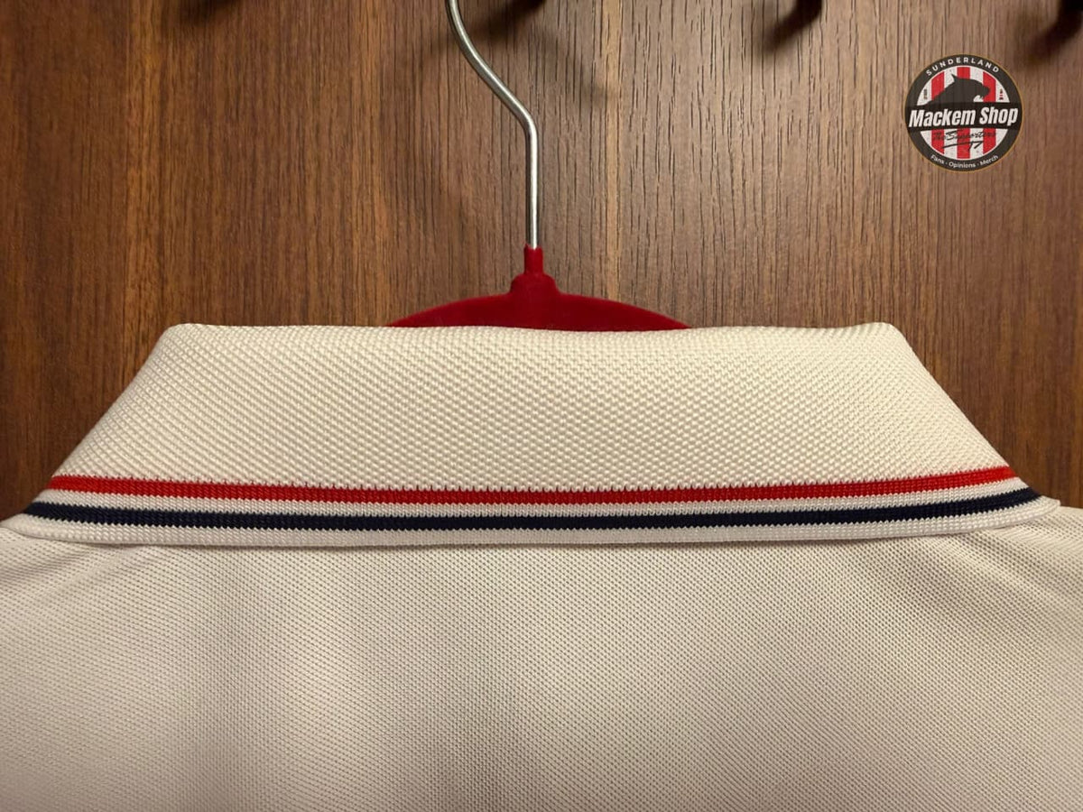 Beige shirt with red, white, and blue stripes on a hanger against a wooden background.