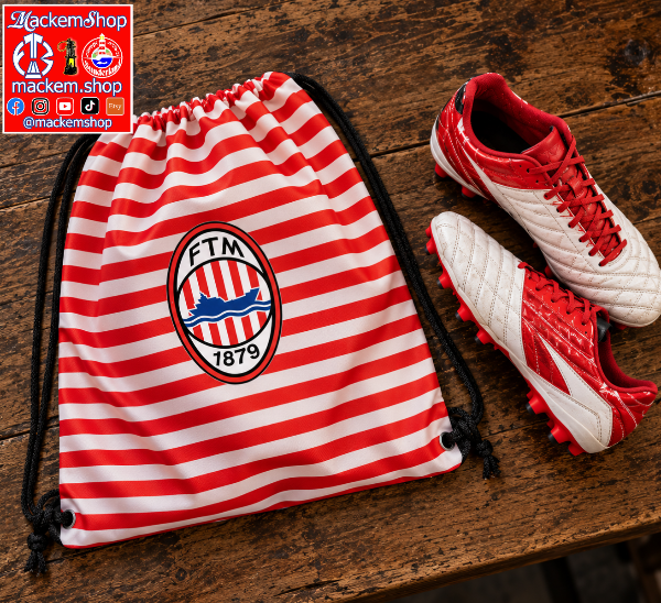 A red and white striped drawstring bag with the FTM 1879 logo, displayed next to a pair of red and white soccer cleats on a rustic wooden table. A 'MackemShop' logo overlay is visible in the top left corner.