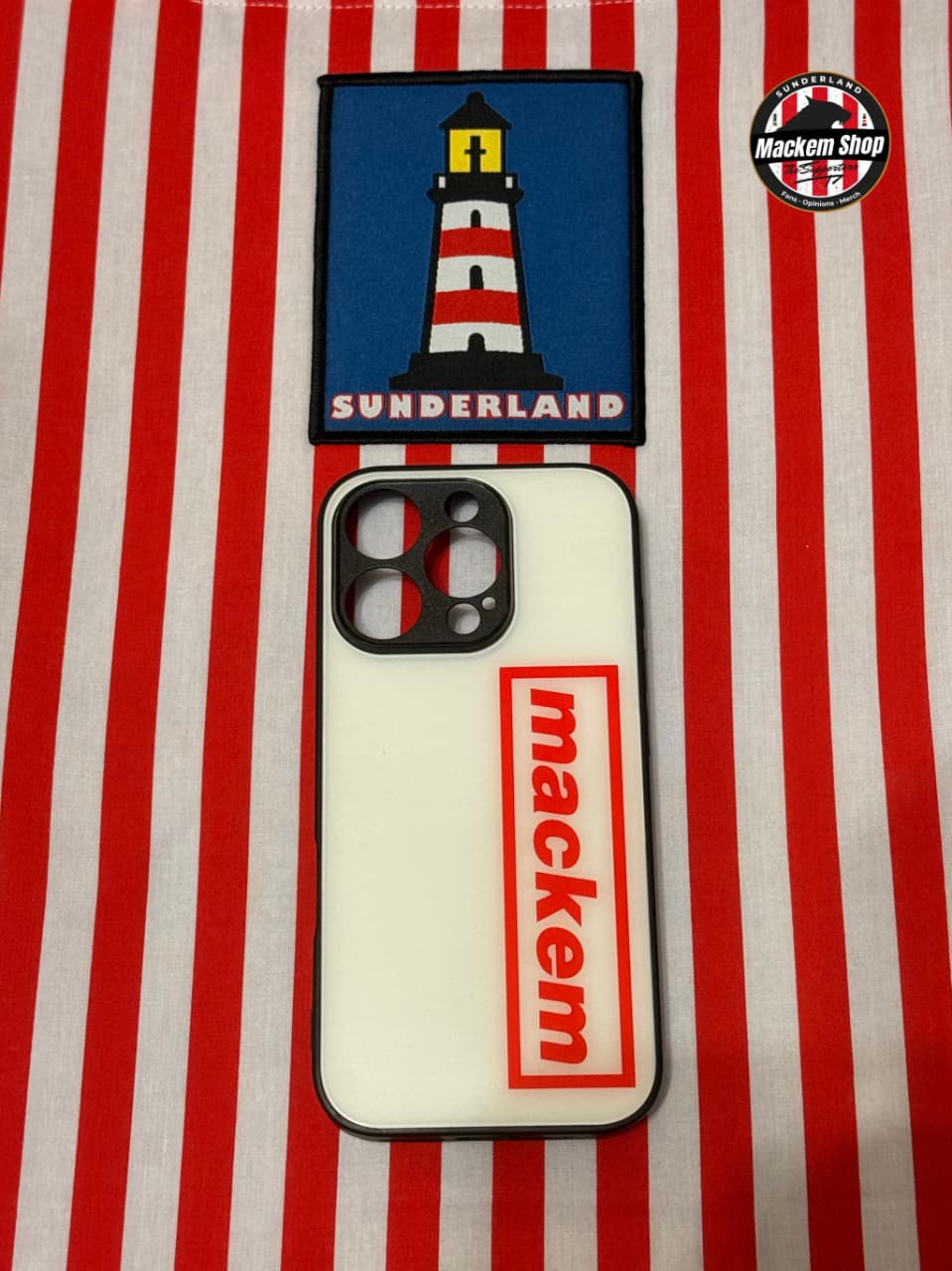 Phone case with lighthouse design and 'mackem' branding on a red and white striped background.
