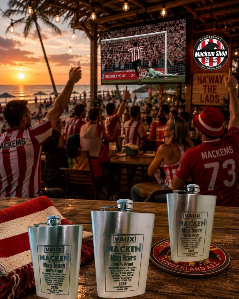 Three silver Vaux Mackem mag tears 10oz Flask bottles displayed on a wooden table at a beach bar, with a crowd cheering in the background watching a sports game at sunset.