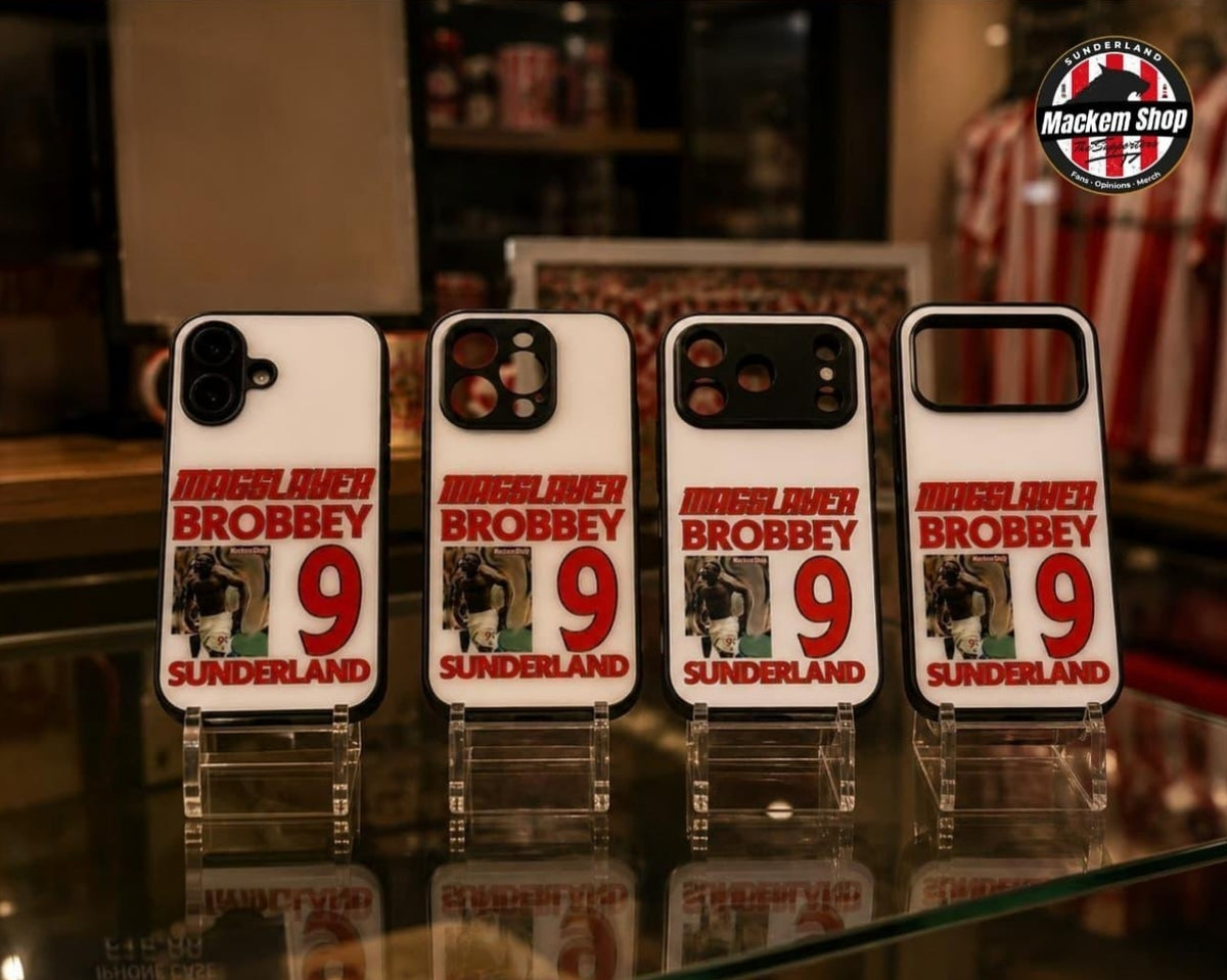 Four white phone cases featuring a red and black 'Maggslayer Brobbey 9 Sunderland' design, displayed on clear acrylic stands on a glass counter inside a store.