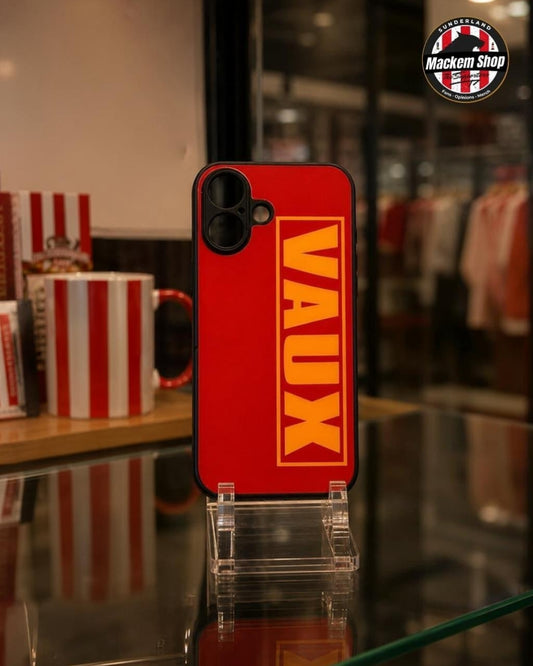 A red phone case with a bold yellow 'VAUX' logo printed vertically, displayed on a clear acrylic stand in a retail store setting.