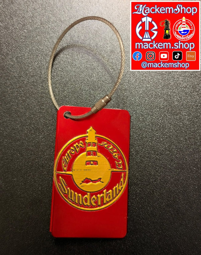 A red luggage tag with a gold 'Sunderland' and lighthouse emblem, attached to a silver wire loop, shown on a dark textured background with a MackemShop social media banner in the top right corner.