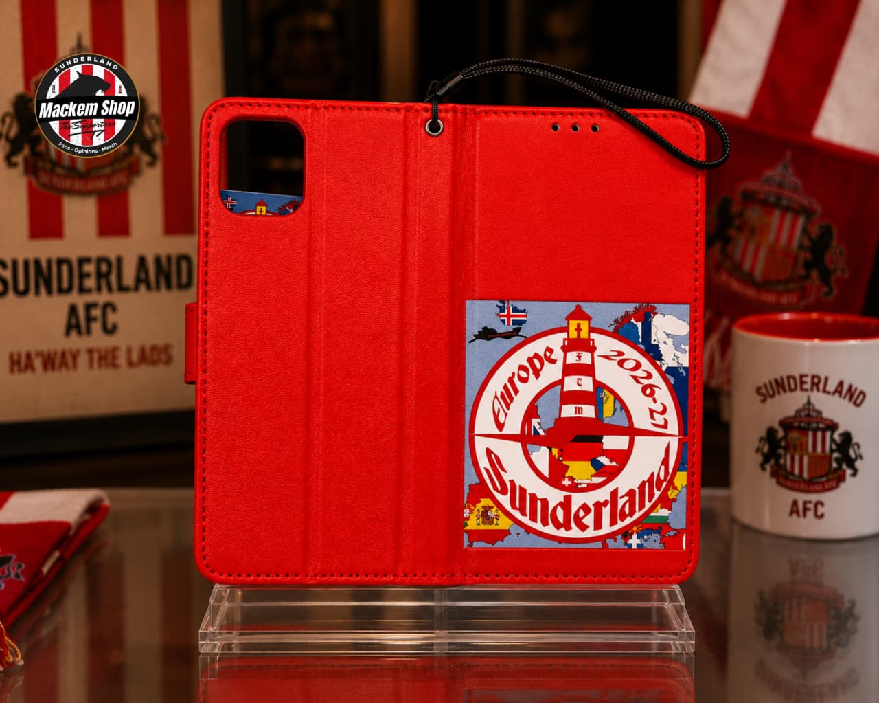 A red folio iPhone case with a Sunderland AFC theme, featuring a large 2026 Europe Champions League lighthouse graphic on the back cover, displayed on a clear stand.