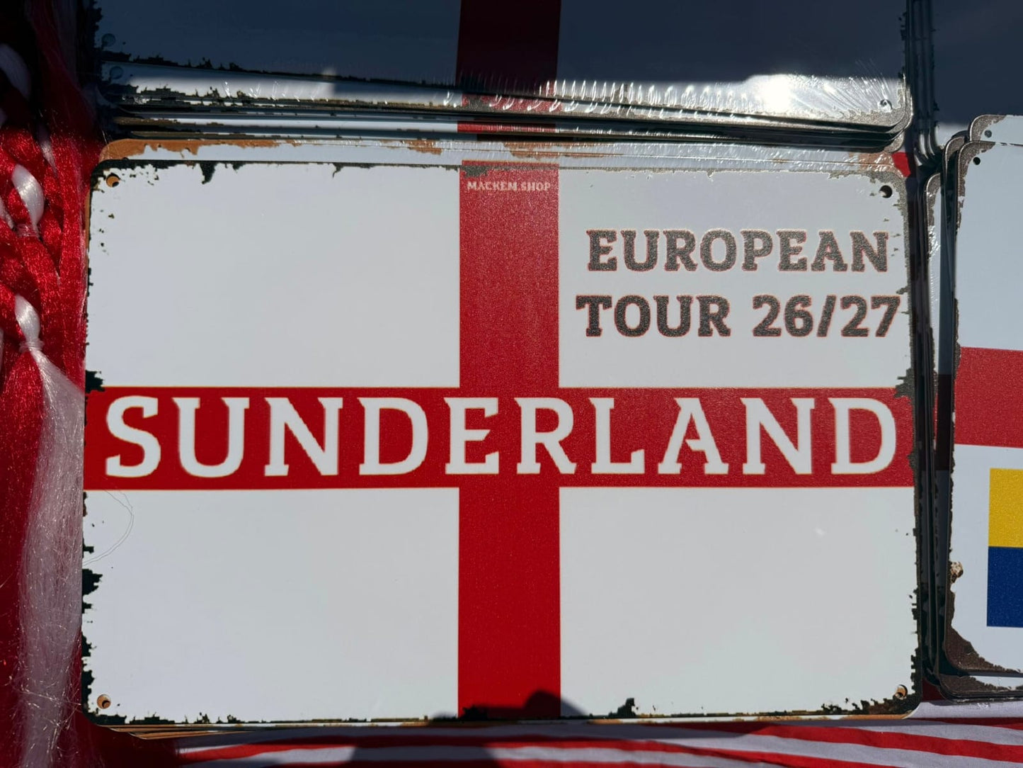 Vintage sign with 'European Tour 26/27 Sunderland' text on a red and white cross background.