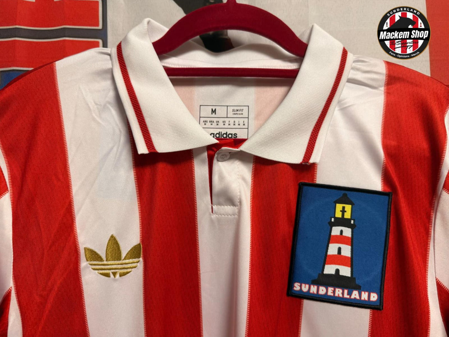Red and white striped shirt with a lighthouse patch on a hanger, Adidas logo visible