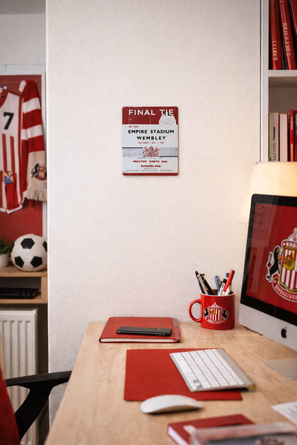 Home office desk with sports-themed decor, including a computer monitor and sports memorabilia.