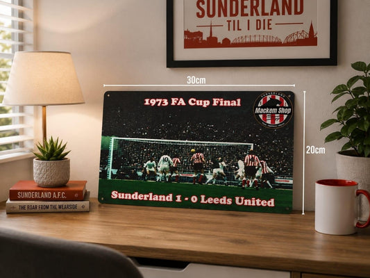 A Sunderland football Metal Sign displayed on a wooden desk in a styled room setting, with dimension labels showing 30cm by 20cm. The Metal Sign features the 1973 FA Cup Final match graphic with Sunderland and Leeds United text.
