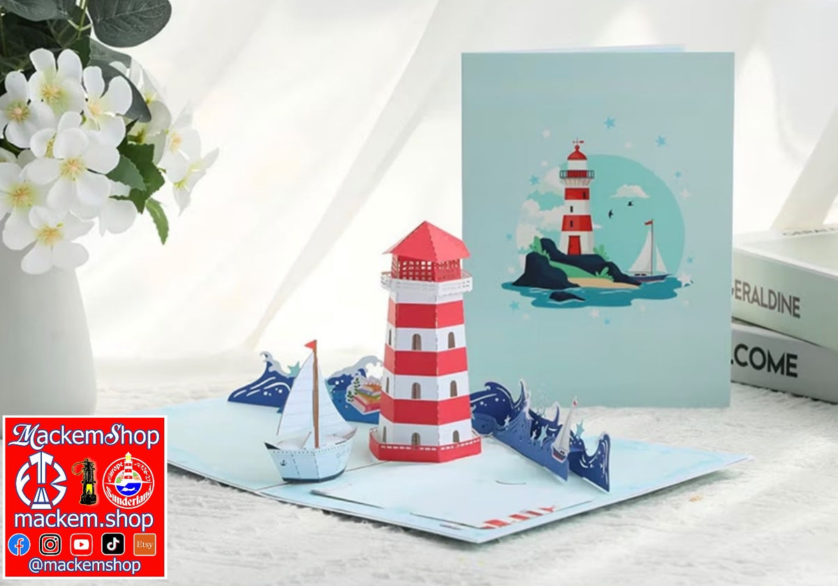A 3D papercraft nautical scene featuring a red and white striped lighthouse, paper boats, and a light blue greeting card with a lighthouse illustration, styled on a white surface with a vase of white flowers and books in the background, with MackemShop logo on downside Left corner.