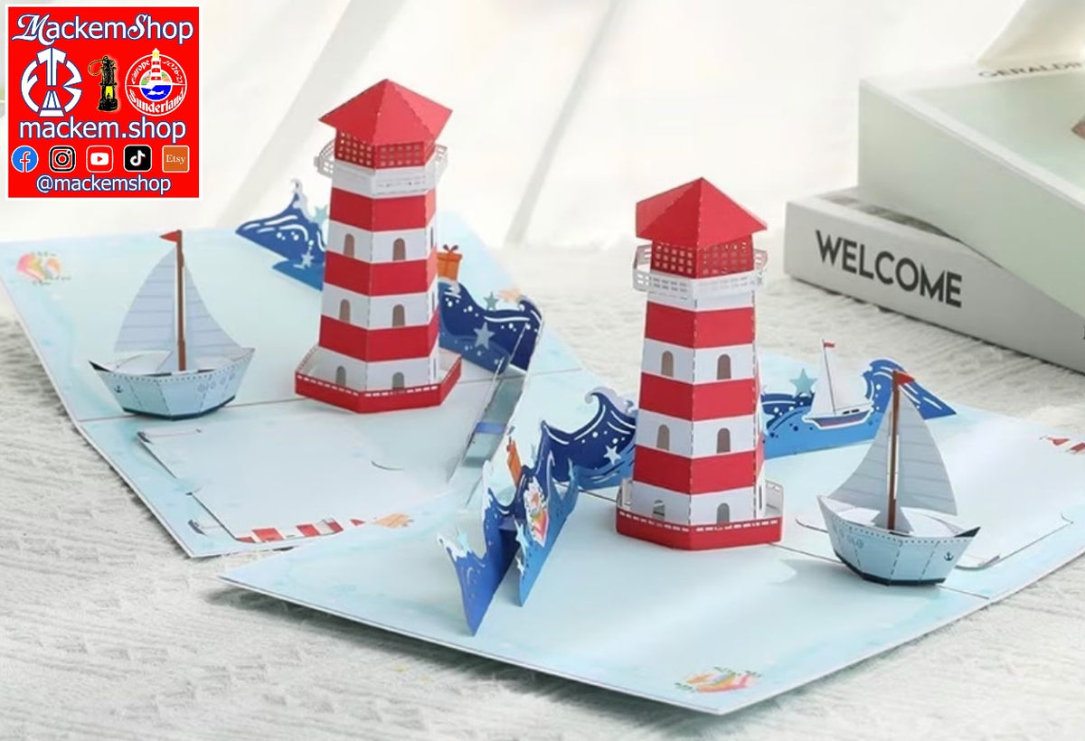 A 3D pop-up paper card featuring a nautical theme with two red and white striped lighthouses, blue waves, and small paper boats, displayed on a light textured surface, with MackemShop Logo visible on top left corner.
