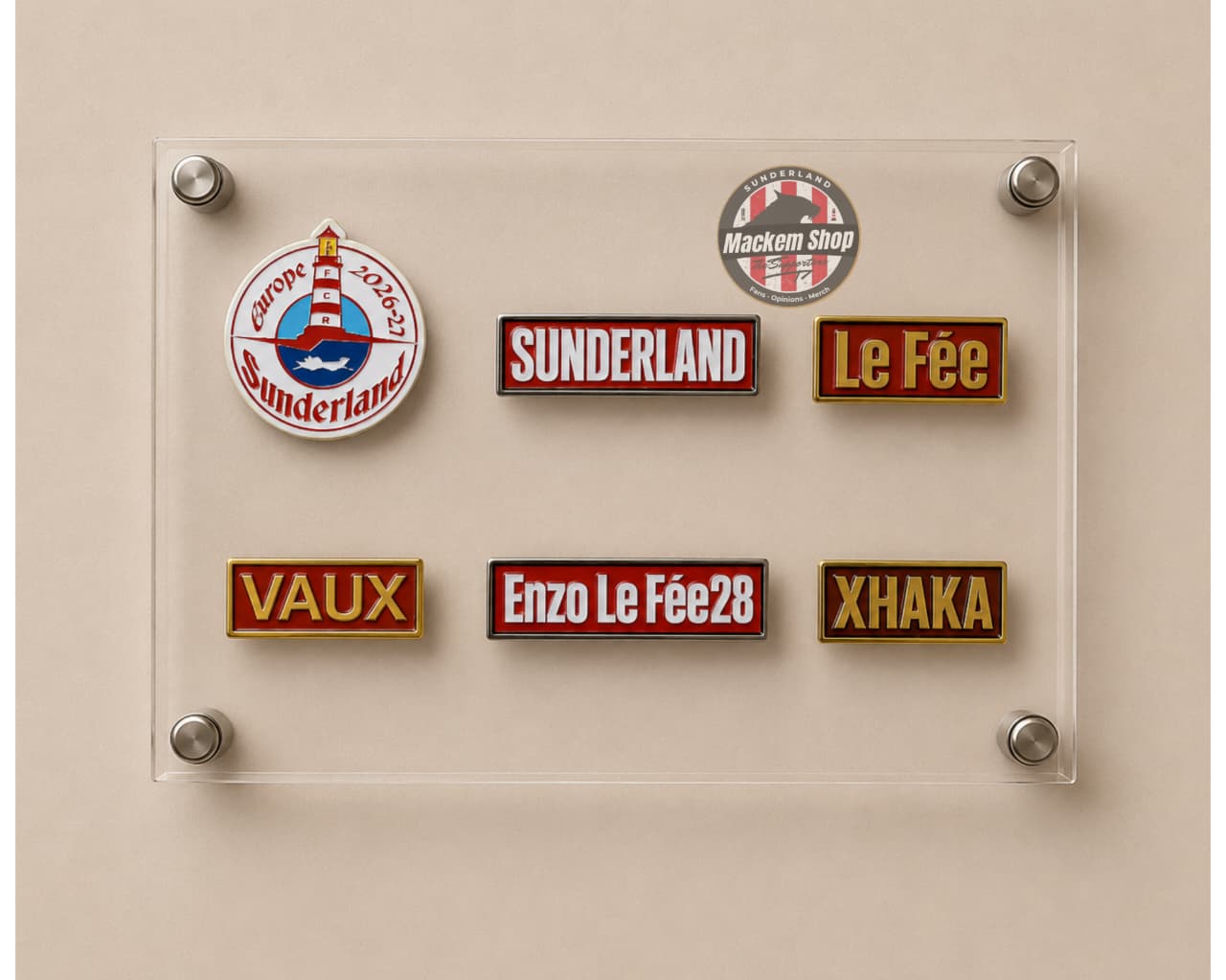 A clear acrylic display board mounted on a beige wall, holding six embroidered Sunderland-themed patches in different colors and designs, including team logos and player names.