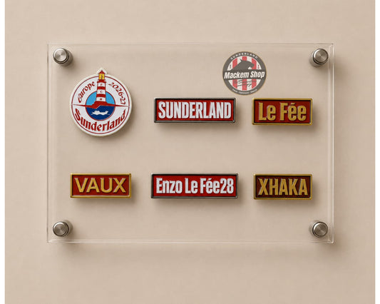 A clear acrylic display board mounted on a beige wall, holding six embroidered Sunderland-themed patches in different colors and designs, including team logos and player names.