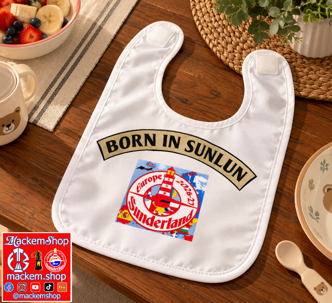 A white baby bib laid flat on a wooden table, printed with a gold 'BORN IN SUNLUN' banner and a colorful 'Europe 2026-27 Sunderland' crest graphic. A mug, plate, spoon, and woven placemat are visible around it, and a 'Mackemshop' logo appears in the lower-left corner.