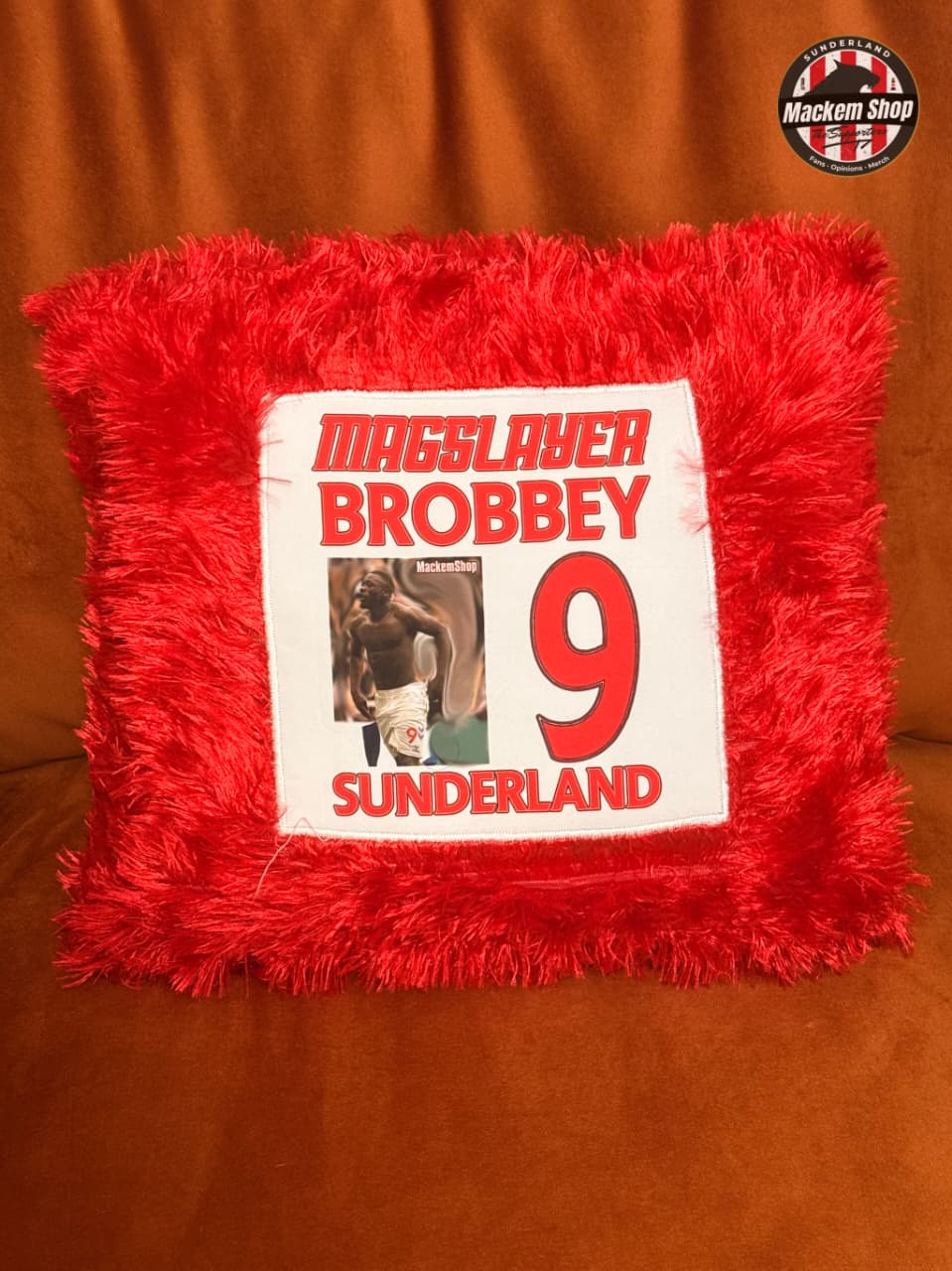 Red textured pillow with a printed design featuring a person and text on an orange background.