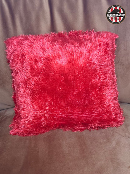 Pink fluffy pillow on a brown couch with a logo in the corner.