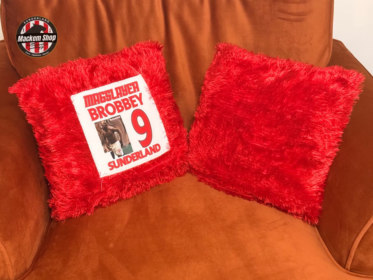 Red textured pillows with a printed label on a brown leather couch