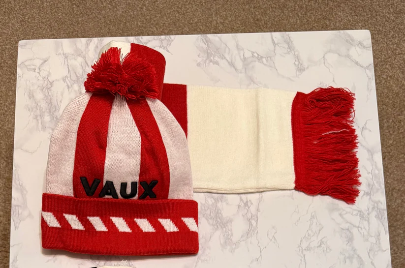 Red and white striped beanie with pom-pom and scarf on a marble surface