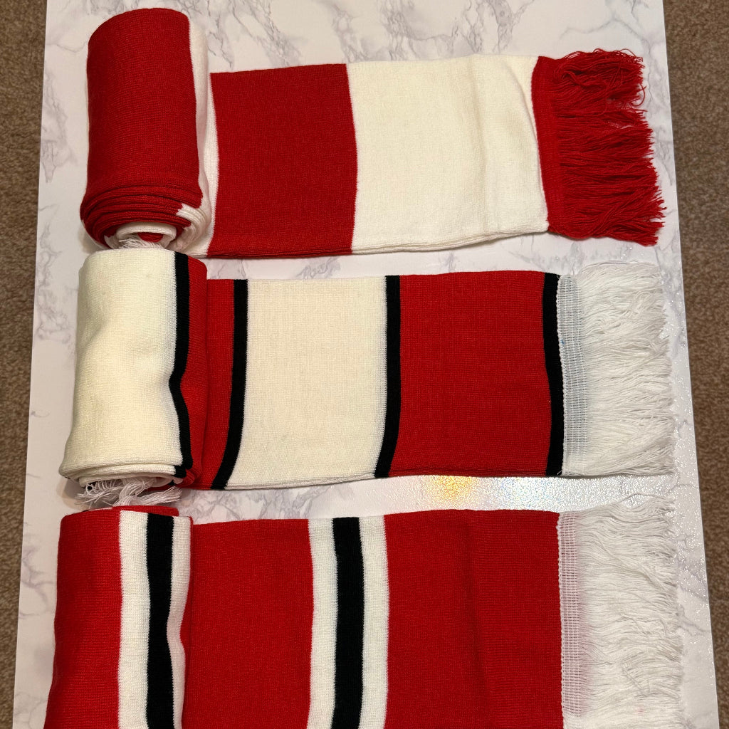Red and white striped scarf with black accents on a white surface.
