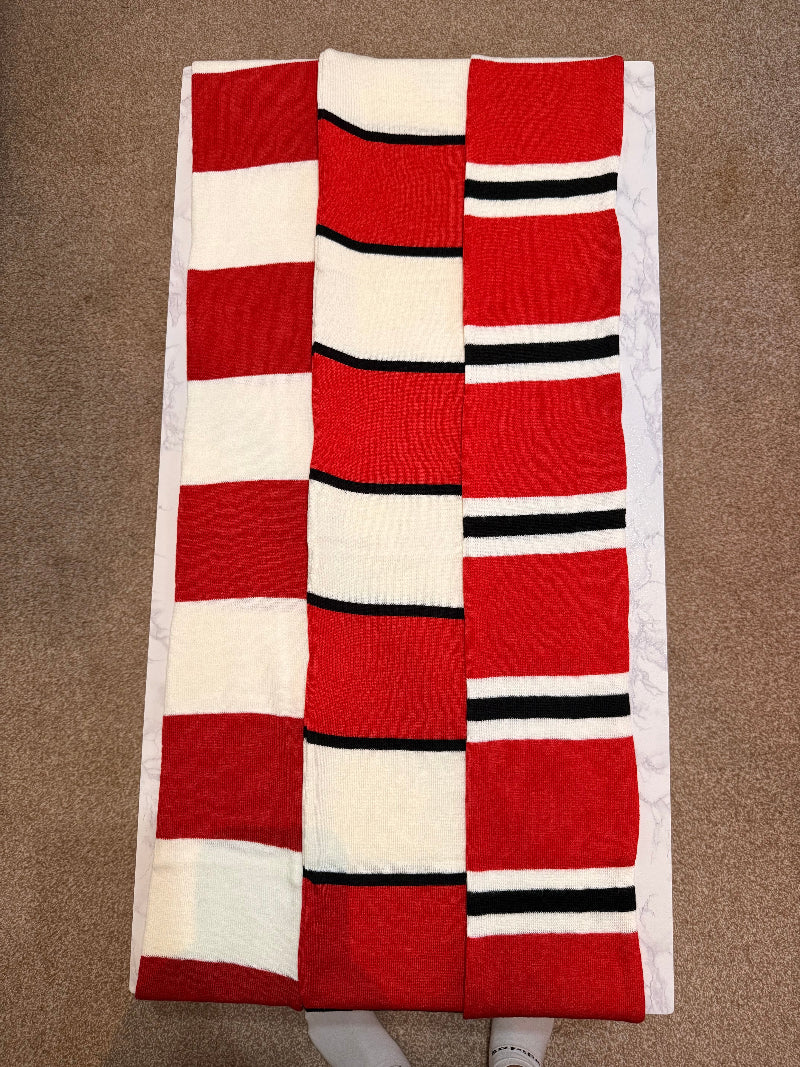 Red, white, and black striped quilt on a brown surface