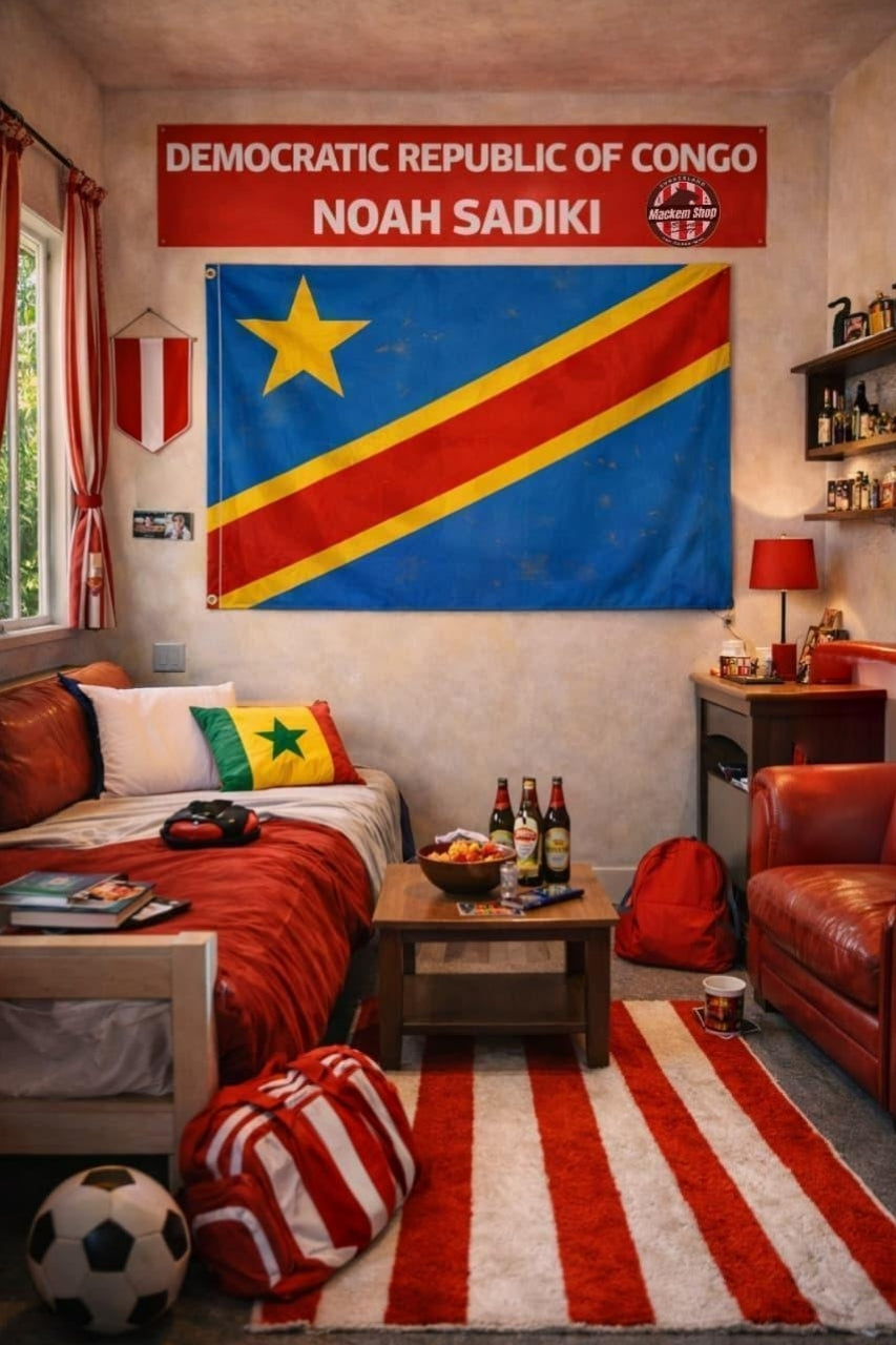 A bedroom scene featuring a large Democratic Republic of Congo flag hanging on the wall, with a red banner above reading 'DEMOCRATIC REPUBLIC OF CONGO NOAH SADIKI'. The room includes a bed with red bedding, a striped rug, a leather chair, and soccer-themed decor.