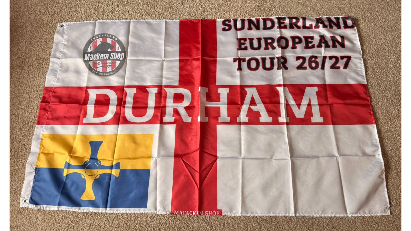 Flag with text 'Sunderland European Tour 26/27 Durham' and various symbols on a beige background