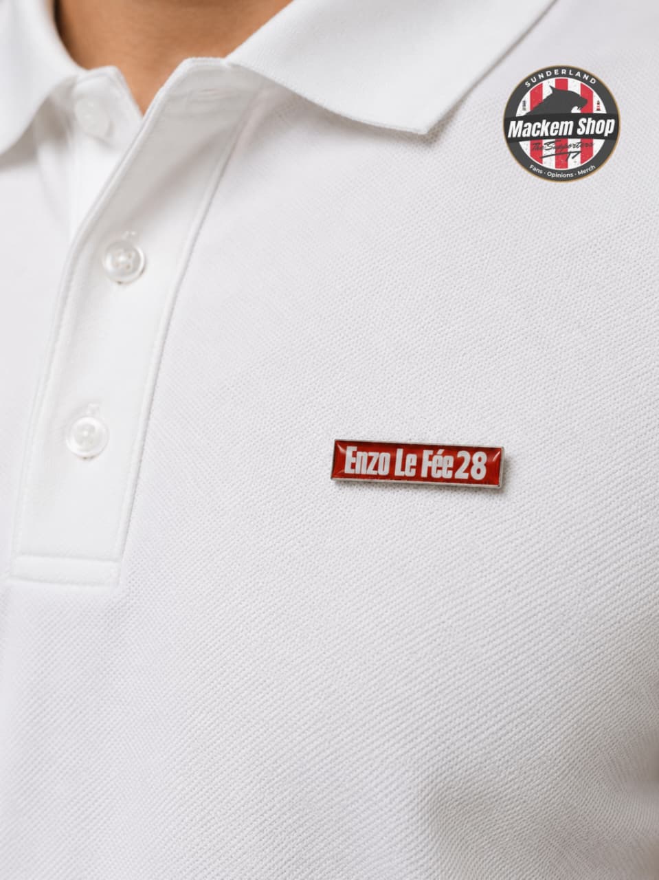 White polo shirt with 'Enzo Le Fée 28' pin badge and Mackem Shop logo on a white polo.