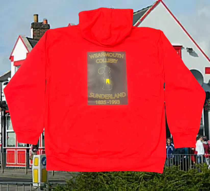 Red hoodie with a printed design on the back, set against an urban background.