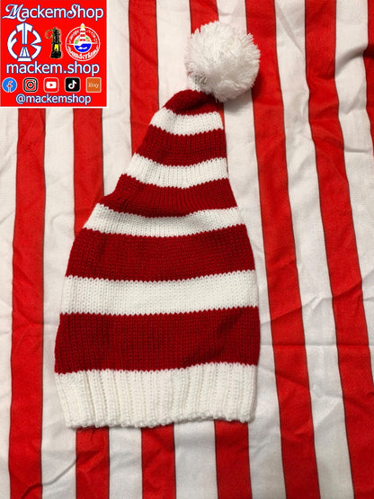 A red and white striped knit hat with a white pom-pom, laid flat on a red and white striped fabric background. A red and white MackemShop logo overlay is visible in the top-left corner.