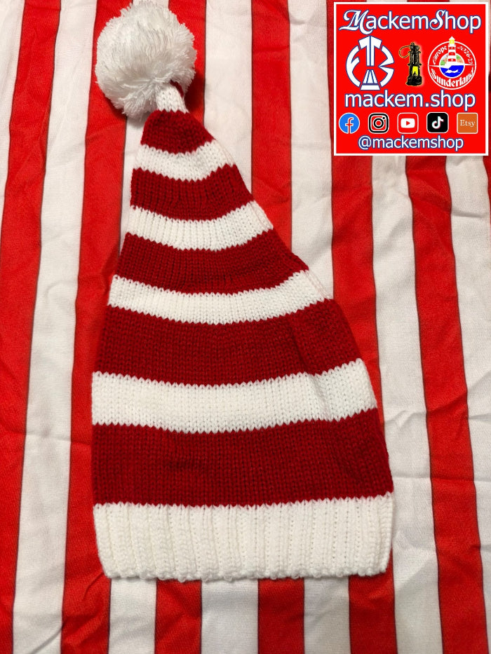 A red and white striped knit Santa hat with a white pom-pom, laid flat on a red and white striped fabric background. A 'MackemShop' brand logo overlay is visible in the top right corner.