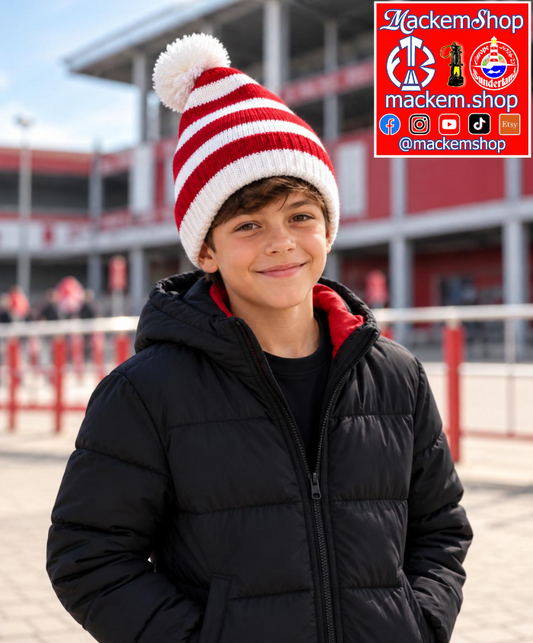 A young boy wearing a red and white striped knit beanie with a pom-pom and a black puffer jacket, standing outdoors in front of a stadium. A red and white 'MackemShop' logo overlay is in the top right corner.
