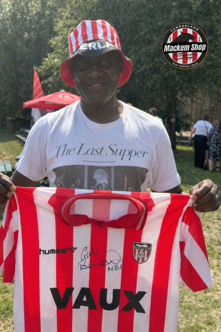 Man holding a red and white sports jersey with visible branding, standing outdoors.