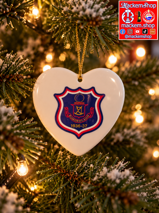 A white heart-shaped ceramic Christmas ornament featuring the Sunderland 1936-37 crest, hanging from a golden string on a decorated Christmas tree with warm lights.