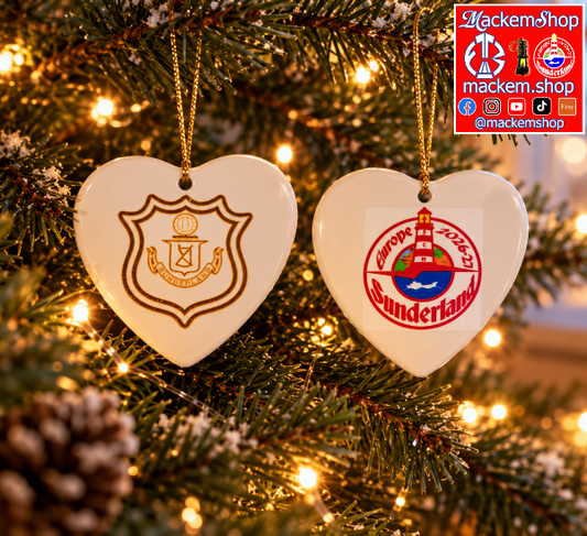 Two heart-shaped ceramic Christmas ornaments hanging on a lit Christmas tree. One ornament is white with a gold shield crest, and the other is white with a red and gold Sunderland logo.