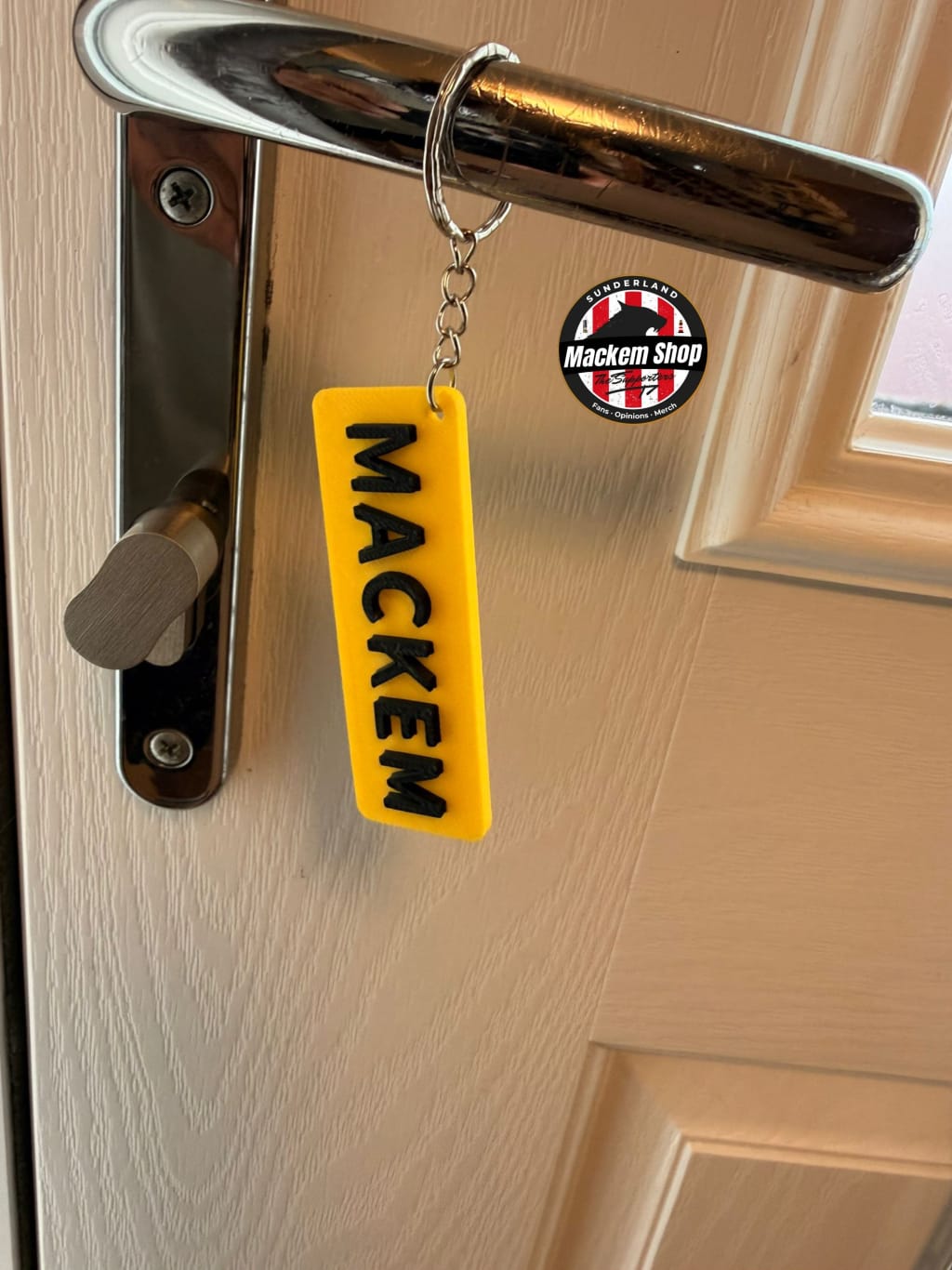 Yellow keychain with 'MACKEM' text attached to a door handle.