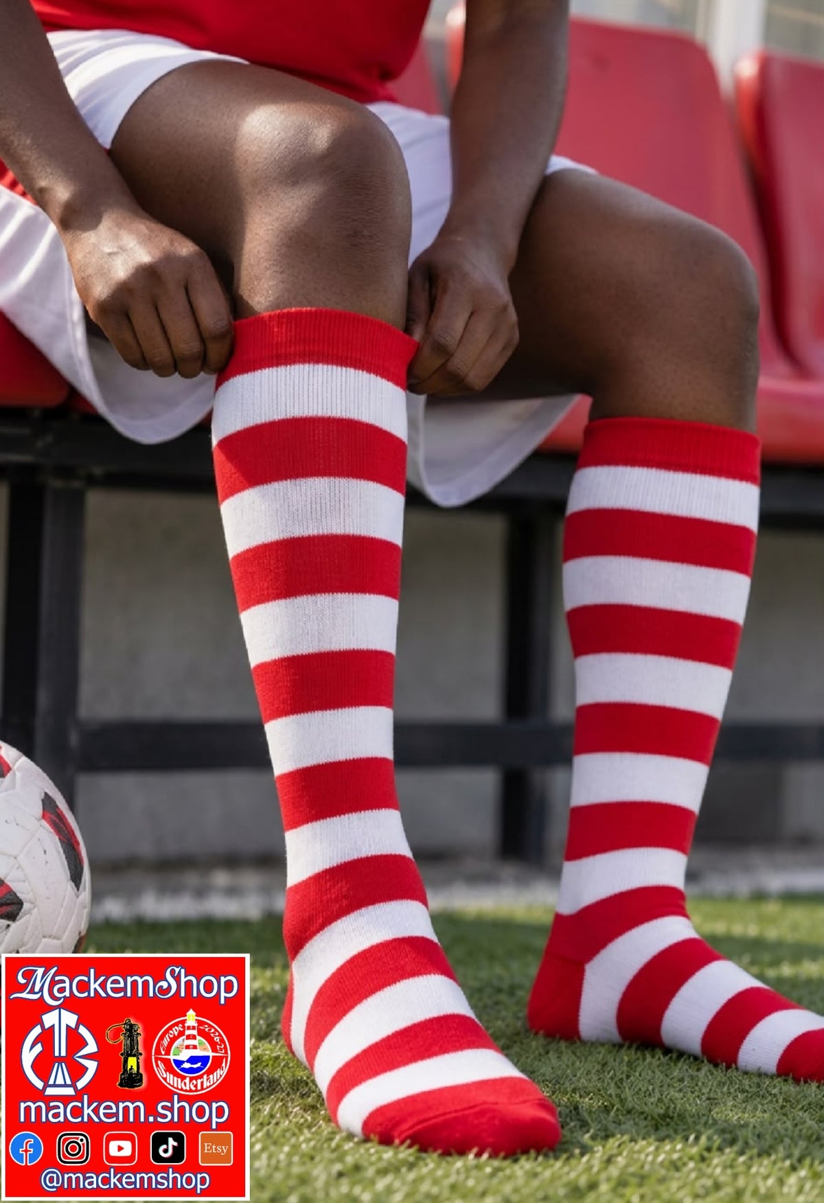 A person sitting on a red stadium bench on a grass field, wearing knee-high socks with bold red and white horizontal stripes. A soccer ball is visible at the lower left, and a red and black 'MackemShop' logo overlay is in the bottom-left corner.