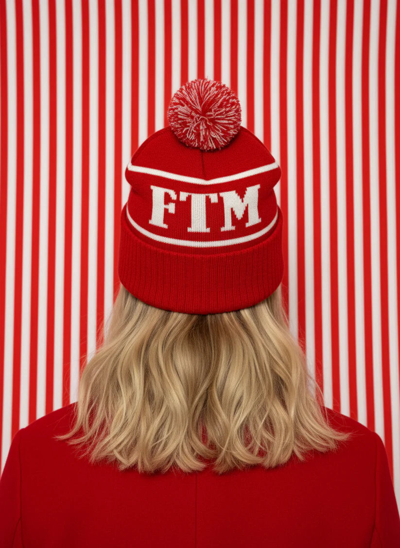 Person wearing a red beanie with 'FTM' on a red and white striped background