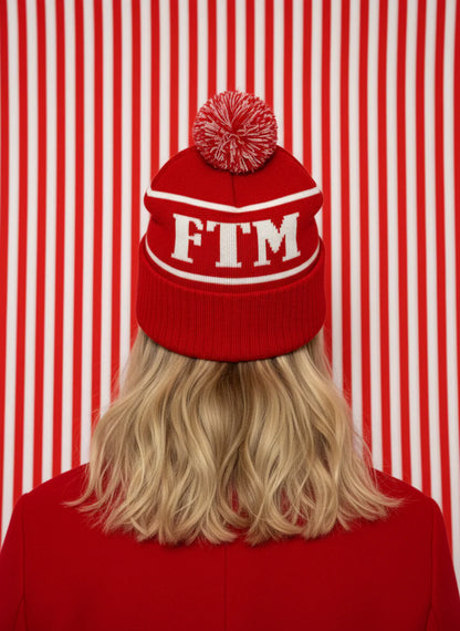 Person wearing a red beanie with 'FTM' on a red and white striped background