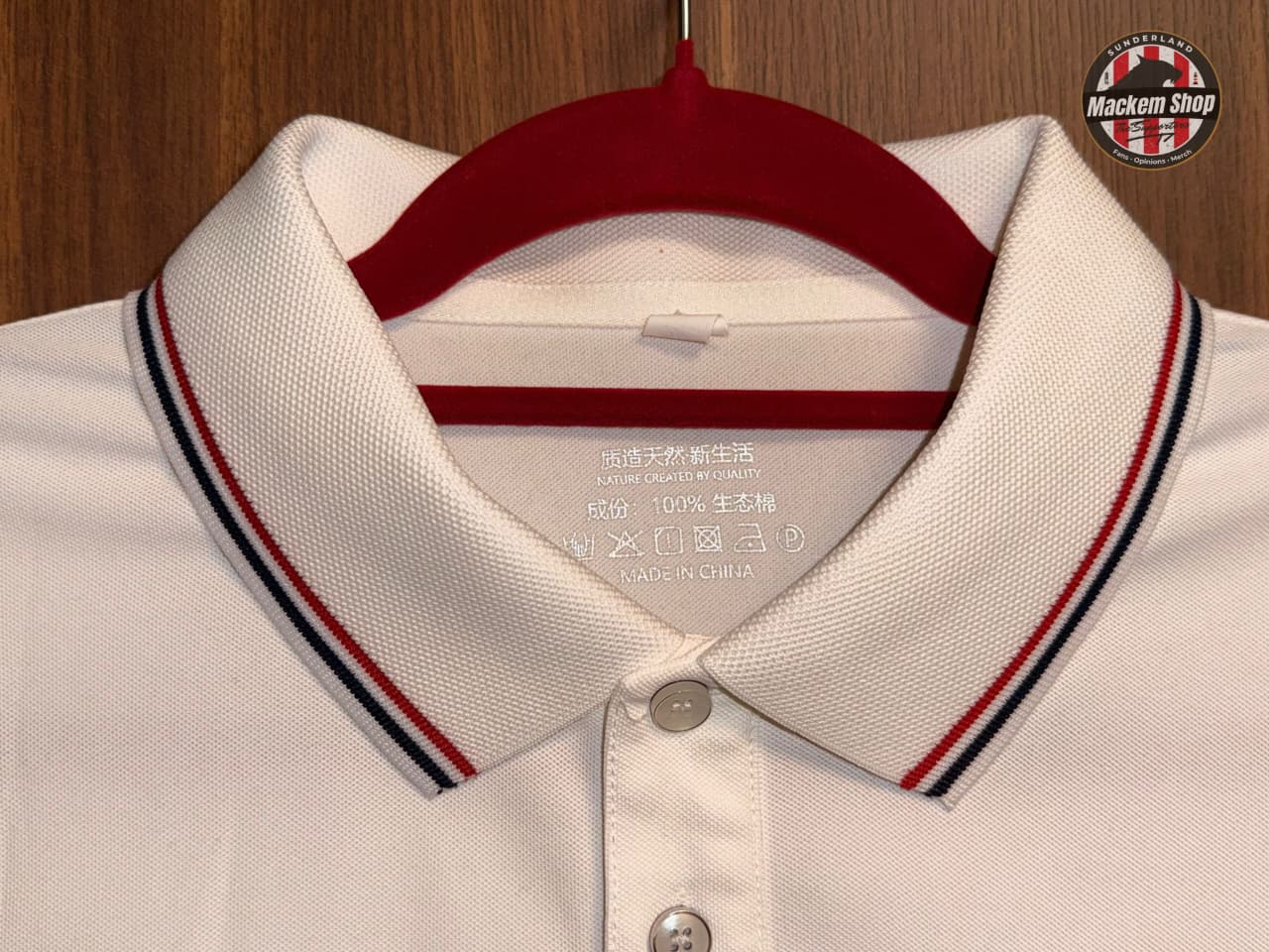 Close-up of a white polo shirt with red and blue collar details on a wooden background.