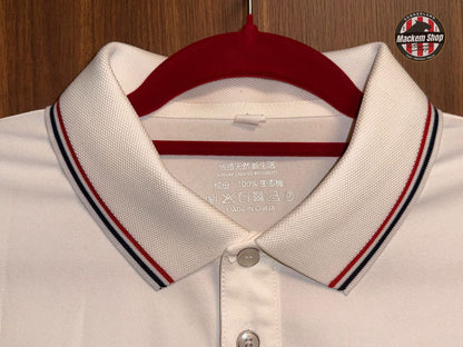 Close-up of a white polo shirt with red and blue collar details on a wooden background.