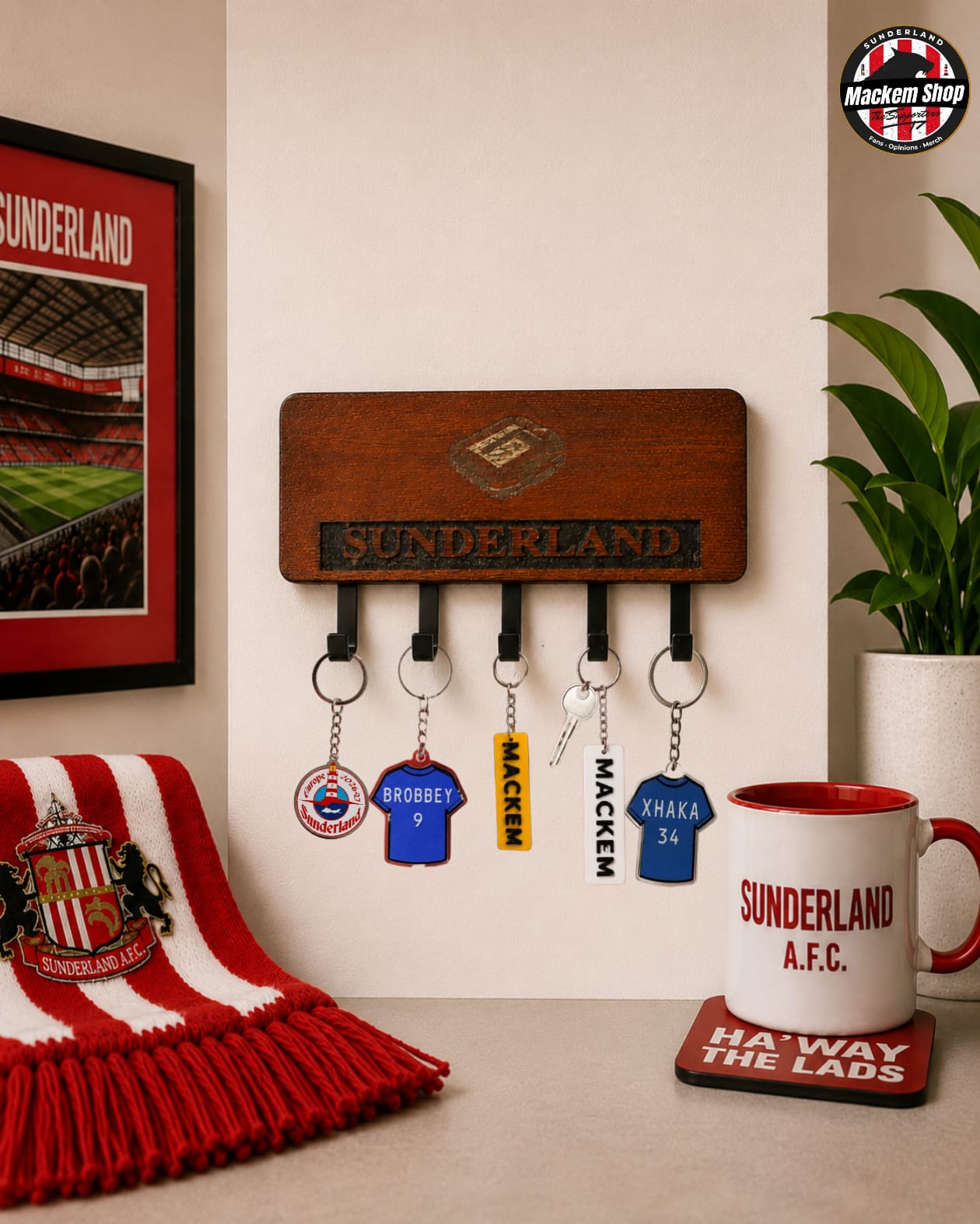 A wooden Sunderland AFC wall-mounted key holder with five hanging keychains, shown in a styled room setting with a red-and-white striped scarf, framed Sunderland poster, plant, and a Sunderland mug.