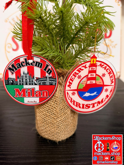 Two round Christmas ornaments hanging from green pine branches in a burlap-wrapped pot. A MackemShop logo is visible in bottom right corner.
