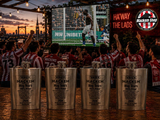Four engraved silver Vaux Mackem mag tears Flask displayed on a bar counter in a crowded outdoor bar scene at sunset, with soccer fans in red and white striped jerseys celebrating in the background.