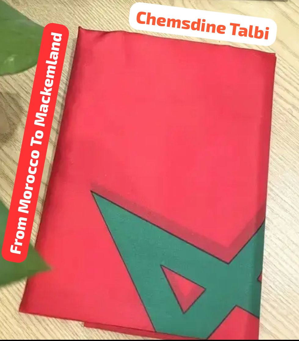 Red and green fabric with geometric patterns on a wooden surface, featuring text 'Chemsdine Talbi' and 'From Morocco To Mackenland'.