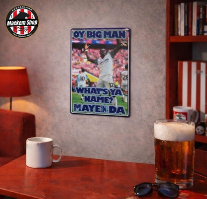 A rectangular metal wall sign featuring a football player celebration with the text 'OY BIG MAN WHAT'S YA NAME? MAYENDA' displayed on a wall above a wooden table with a mug, beer glass, and sunglasses. A circular 'Mackem Shop' watermark is visible in the top-left corner.